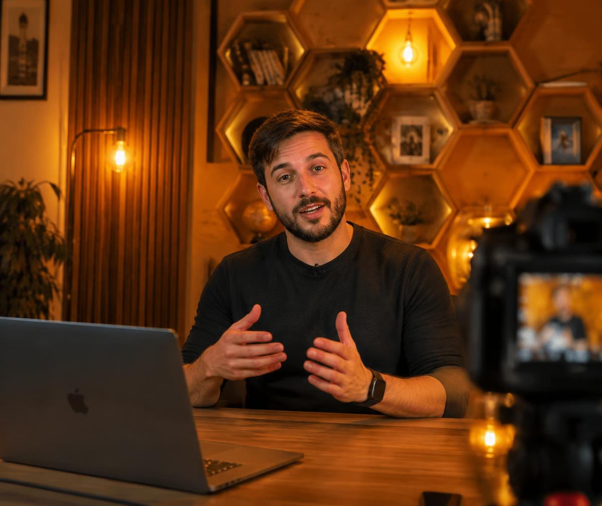 A creator recording an online lesson in a warm studio with honeycomb shelves